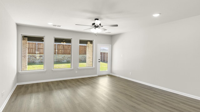 spare room featuring visible vents, baseboards, a ceiling fan, and dark wood finished floors