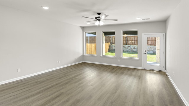 unfurnished room featuring visible vents, ceiling fan, a wealth of natural light, and dark wood finished floors