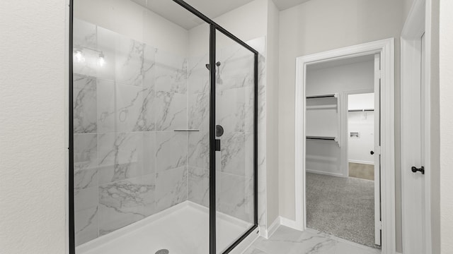 bathroom featuring marble finish floor, a marble finish shower, baseboards, and a walk in closet