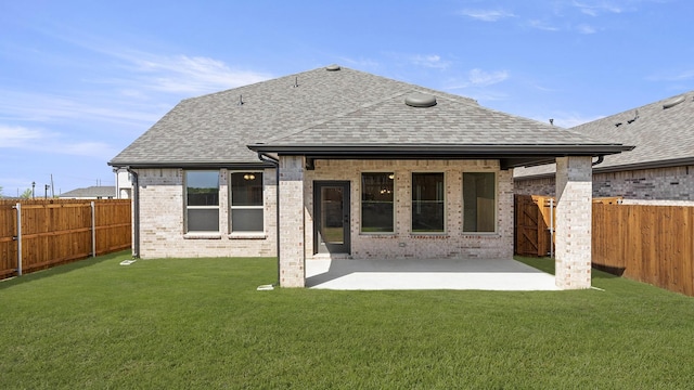 back of property with brick siding, a fenced backyard, a shingled roof, and a yard