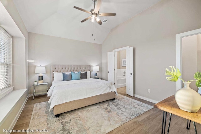 bedroom with ensuite bath, wood-type flooring, and vaulted ceiling