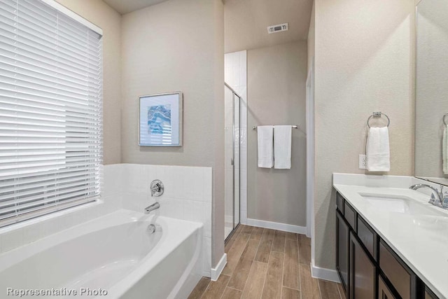 bathroom with vanity and shower with separate bathtub