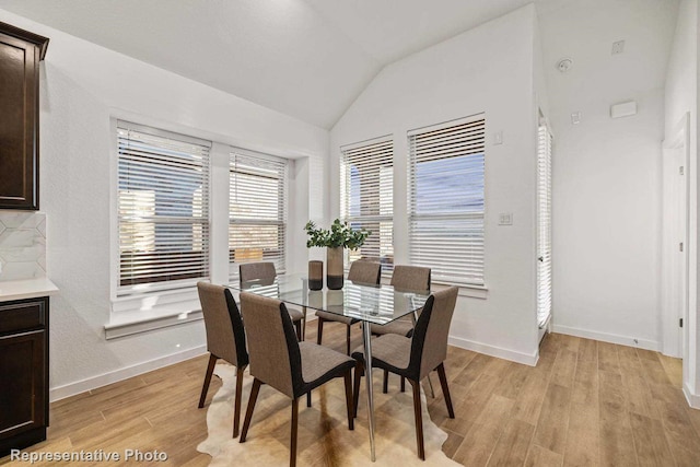 dining space featuring lofted ceiling and light wood-type flooring