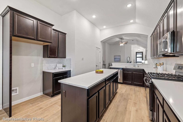 kitchen featuring sink, ceiling fan, appliances with stainless steel finishes, vaulted ceiling, and light wood-type flooring