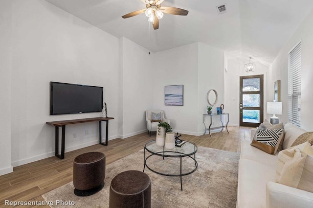 living room with lofted ceiling, ceiling fan with notable chandelier, and wood-type flooring