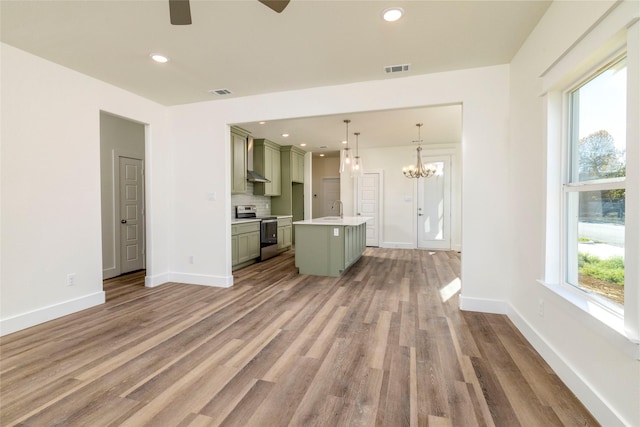 unfurnished living room with plenty of natural light, hardwood / wood-style floors, ceiling fan with notable chandelier, and sink