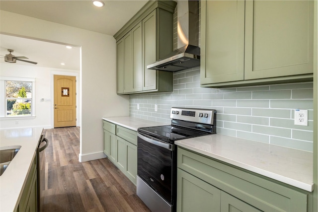 kitchen with green cabinetry, wall chimney exhaust hood, ceiling fan, appliances with stainless steel finishes, and dark hardwood / wood-style flooring