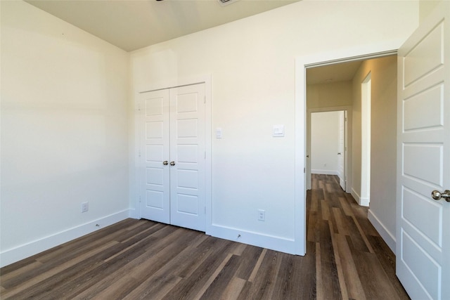 unfurnished bedroom featuring dark hardwood / wood-style floors and a closet