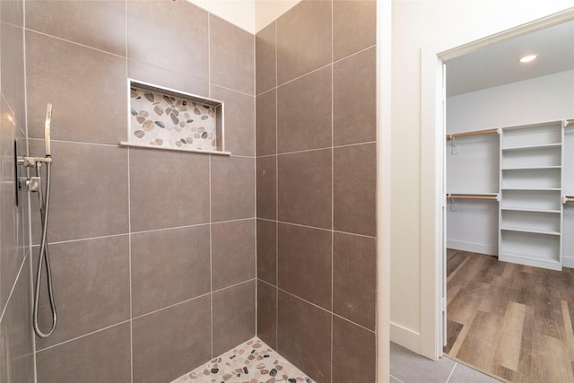 bathroom featuring wood-type flooring and a tile shower