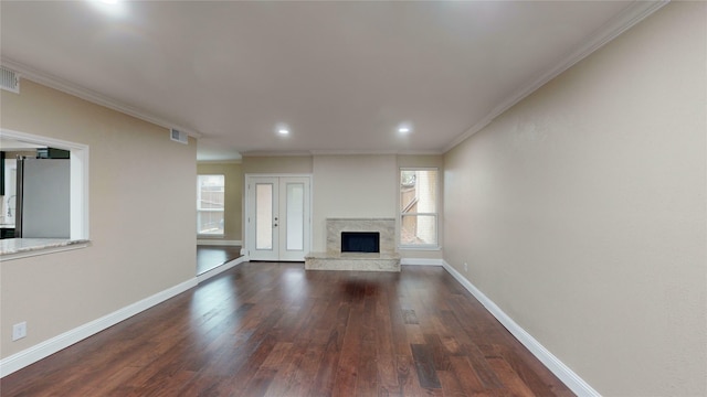 unfurnished living room featuring french doors, dark hardwood / wood-style floors, ornamental molding, and a premium fireplace