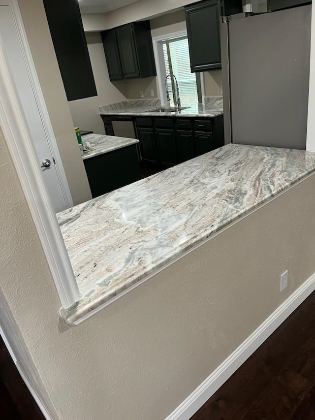 kitchen with dark hardwood / wood-style flooring, stainless steel fridge, sink, and light stone countertops