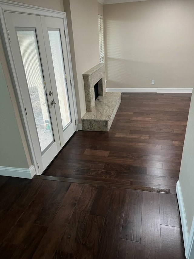 unfurnished living room featuring french doors, a high end fireplace, and dark hardwood / wood-style floors