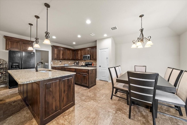 kitchen with tasteful backsplash, dark brown cabinets, stainless steel appliances, sink, and an island with sink