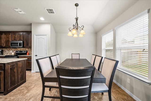 dining space with light tile patterned floors, lofted ceiling, and an inviting chandelier