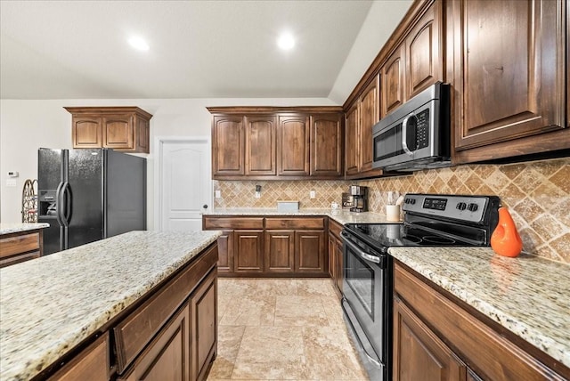 kitchen with appliances with stainless steel finishes, tasteful backsplash, and light stone counters