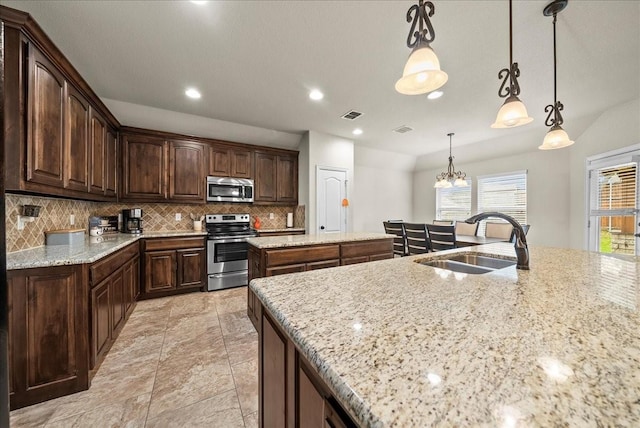 kitchen featuring a center island with sink, sink, decorative light fixtures, dark brown cabinets, and stainless steel appliances