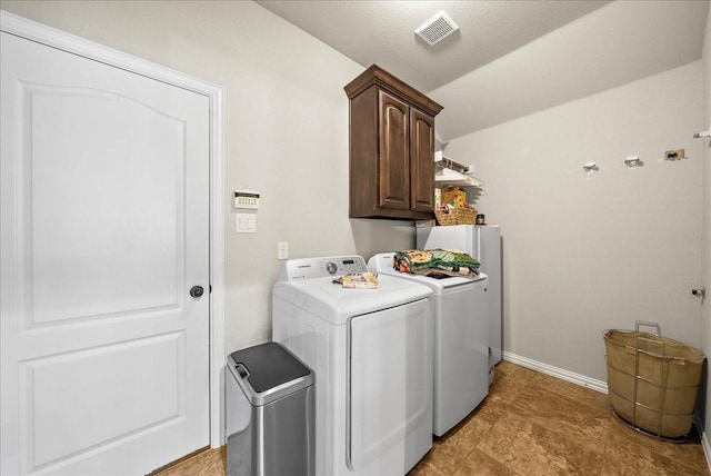 laundry area featuring washing machine and clothes dryer, cabinets, and a textured ceiling