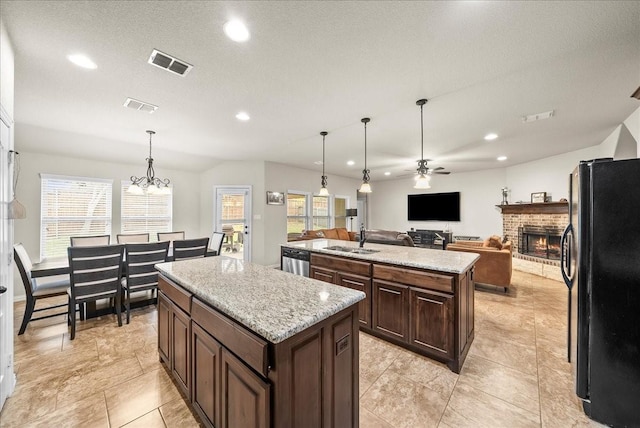 kitchen with a wealth of natural light, black fridge, a kitchen island, and ceiling fan with notable chandelier