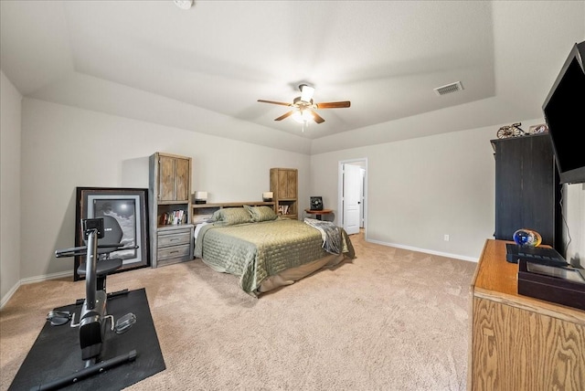 carpeted bedroom with a raised ceiling and ceiling fan