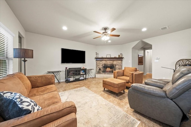 living room featuring ceiling fan and a fireplace