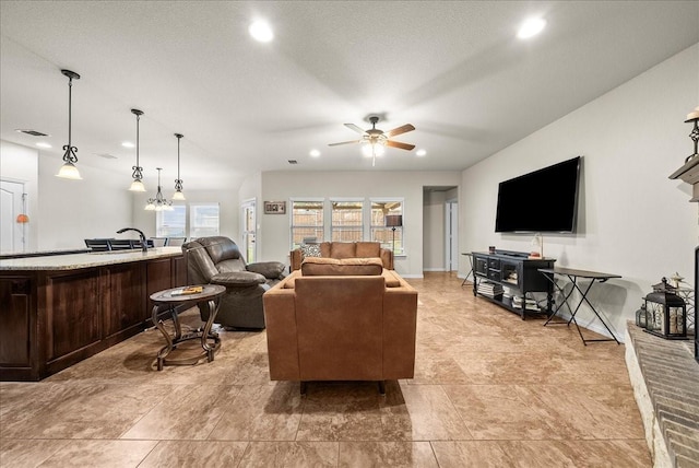 living room featuring a textured ceiling, ceiling fan, and sink