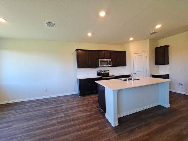 kitchen featuring sink, stainless steel appliances, dark hardwood / wood-style floors, dark brown cabinets, and a center island with sink