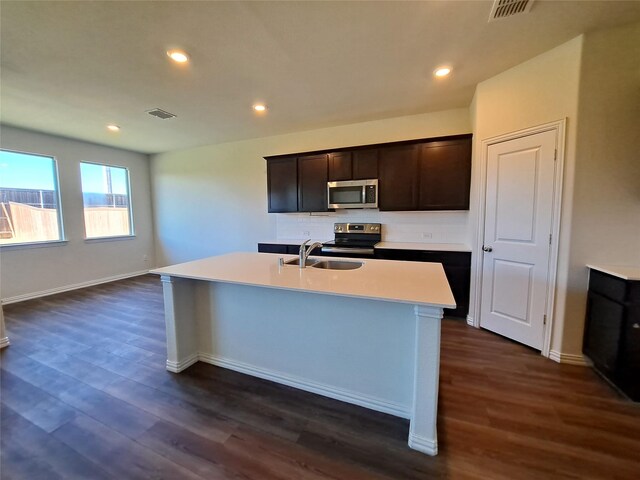 kitchen with dark hardwood / wood-style flooring, stainless steel appliances, a kitchen island with sink, and sink