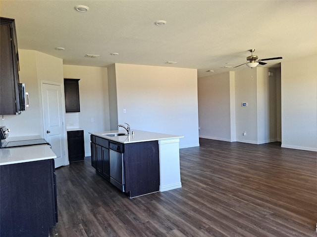 kitchen featuring dark wood-type flooring, a center island with sink, sink, ceiling fan, and appliances with stainless steel finishes