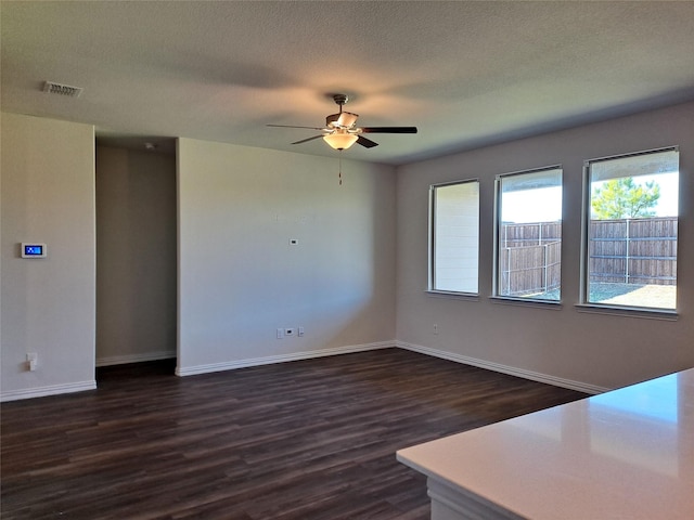 empty room with a textured ceiling, dark hardwood / wood-style flooring, and ceiling fan