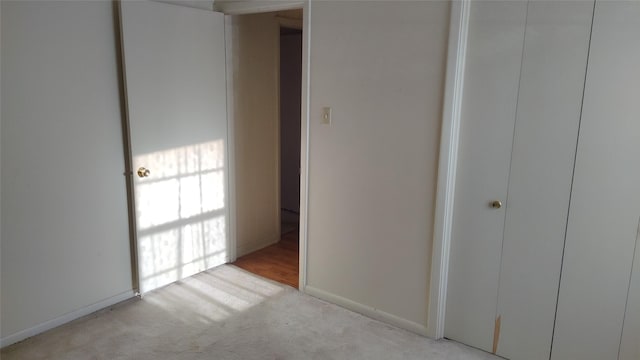 unfurnished bedroom with light carpet and a closet