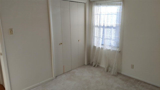 unfurnished bedroom with light colored carpet and a closet