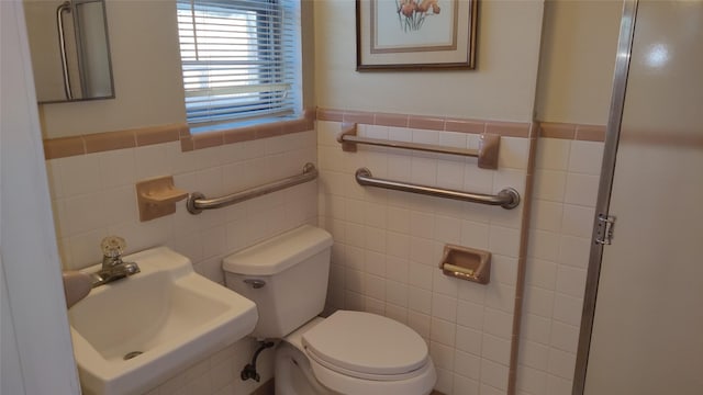 bathroom with toilet, sink, and tile walls