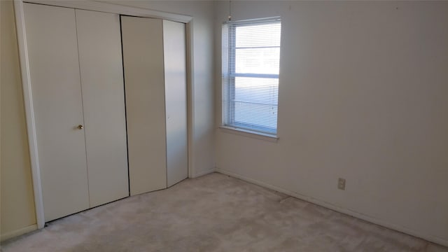 unfurnished bedroom with light carpet and a closet