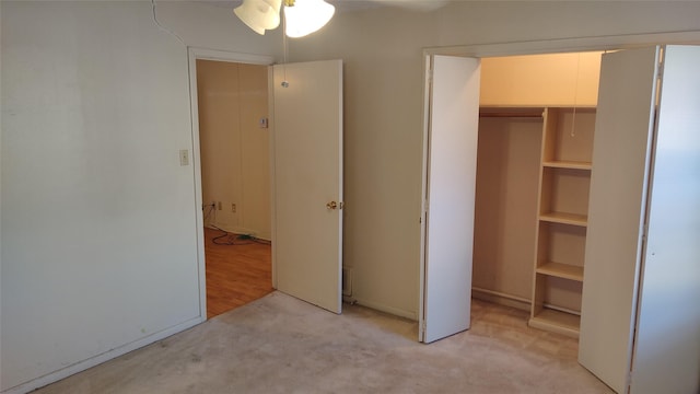 unfurnished bedroom with ceiling fan, light carpet, and a closet