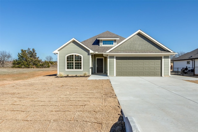 view of front of home with driveway, an attached garage, and roof with shingles