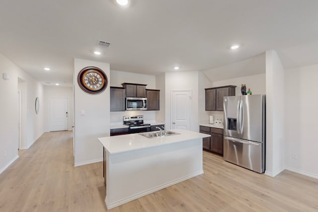 kitchen with a kitchen island with sink, dark brown cabinets, light hardwood / wood-style floors, and appliances with stainless steel finishes