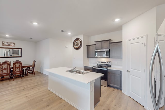 kitchen featuring light hardwood / wood-style floors, sink, stainless steel appliances, and a kitchen island with sink