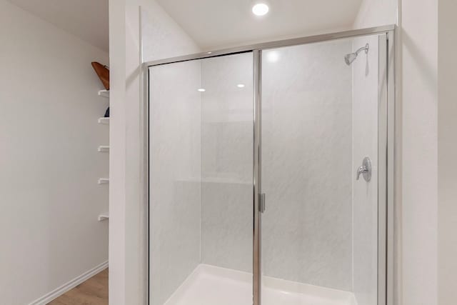 bathroom with wood-type flooring and an enclosed shower