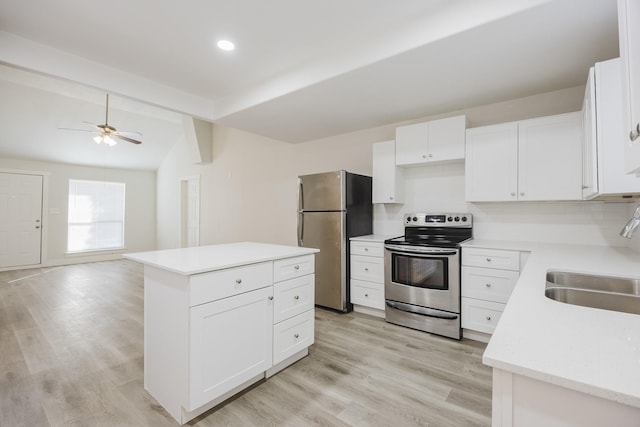 kitchen with light countertops, appliances with stainless steel finishes, open floor plan, white cabinets, and a sink