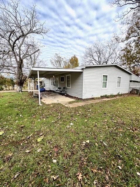 rear view of property featuring a carport and a lawn