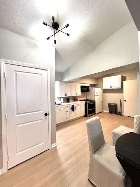 living room with a textured ceiling, light hardwood / wood-style flooring, and vaulted ceiling