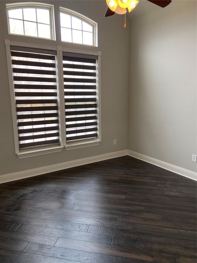 empty room featuring ceiling fan, a healthy amount of sunlight, and dark hardwood / wood-style flooring