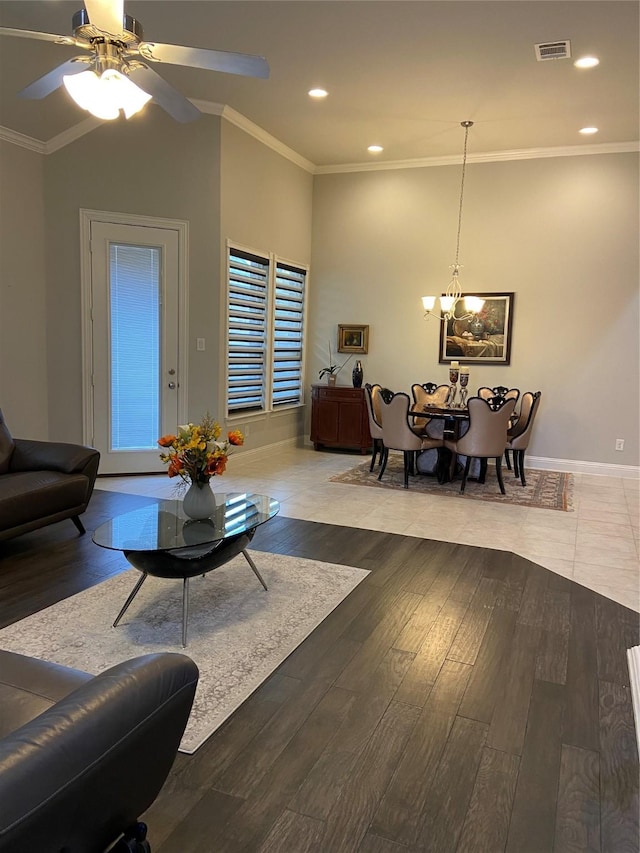 living room with hardwood / wood-style floors, crown molding, ceiling fan with notable chandelier, and vaulted ceiling