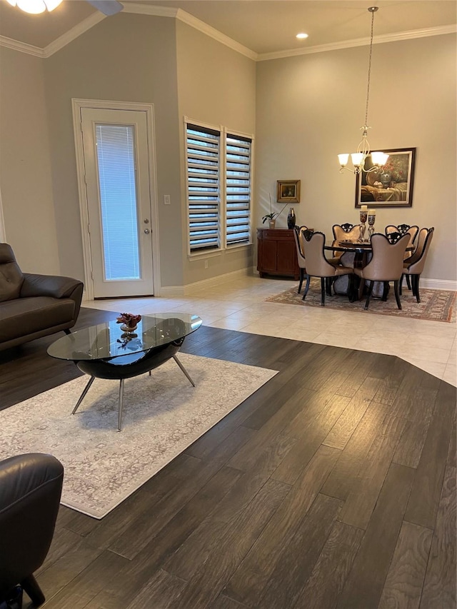 living room featuring wood-type flooring, lofted ceiling, crown molding, and a notable chandelier