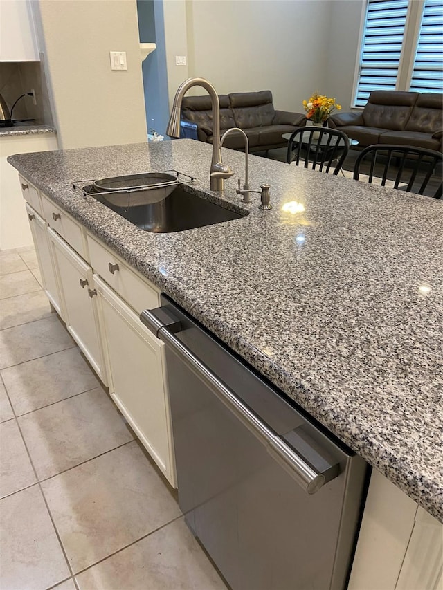 kitchen featuring dishwasher, light tile patterned floors, sink, and stone counters