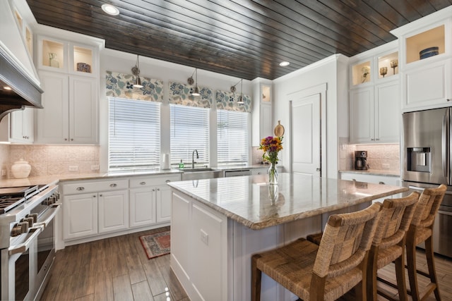 kitchen featuring a center island, decorative light fixtures, white cabinetry, stainless steel appliances, and wood ceiling