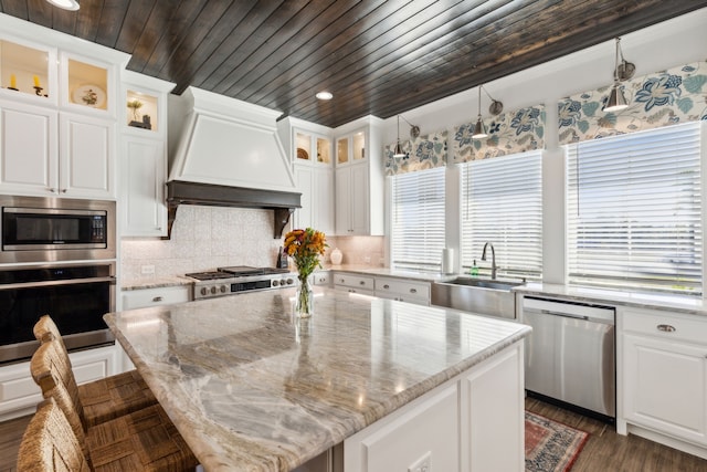 kitchen featuring white cabinetry, a center island, stainless steel appliances, and custom range hood