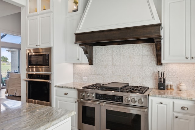 kitchen with white cabinets, appliances with stainless steel finishes, decorative backsplash, and custom exhaust hood