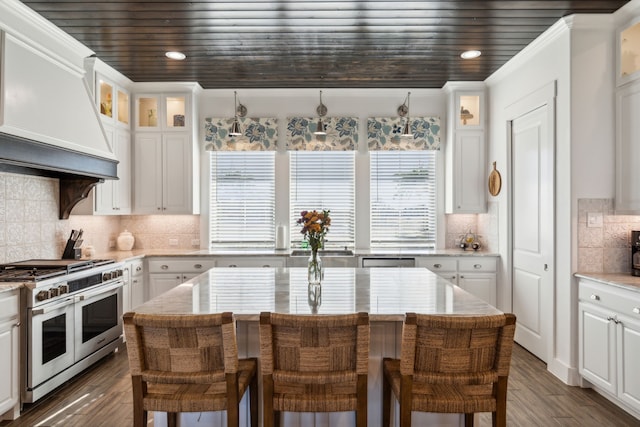 kitchen with double oven range, premium range hood, white cabinets, a kitchen island, and a breakfast bar area