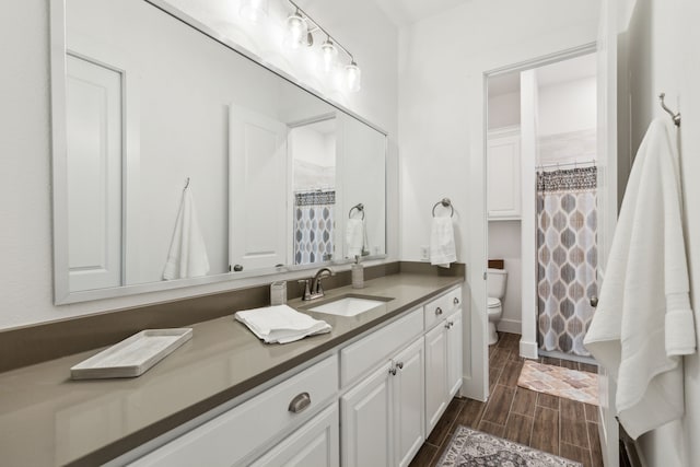 bathroom featuring walk in shower, hardwood / wood-style floors, vanity, and toilet